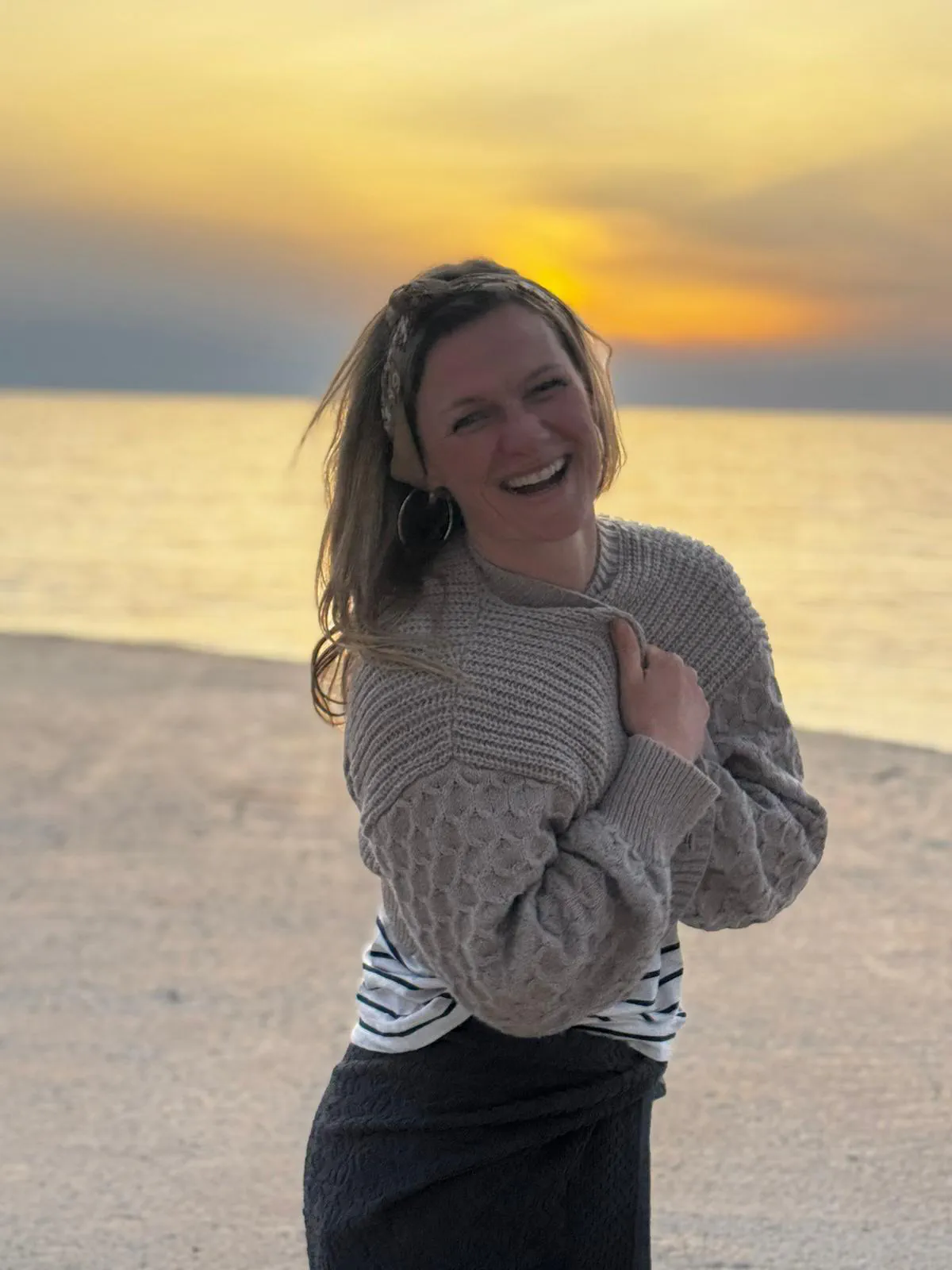 Dana lacht am Strand vor goldenem Abendhimmel