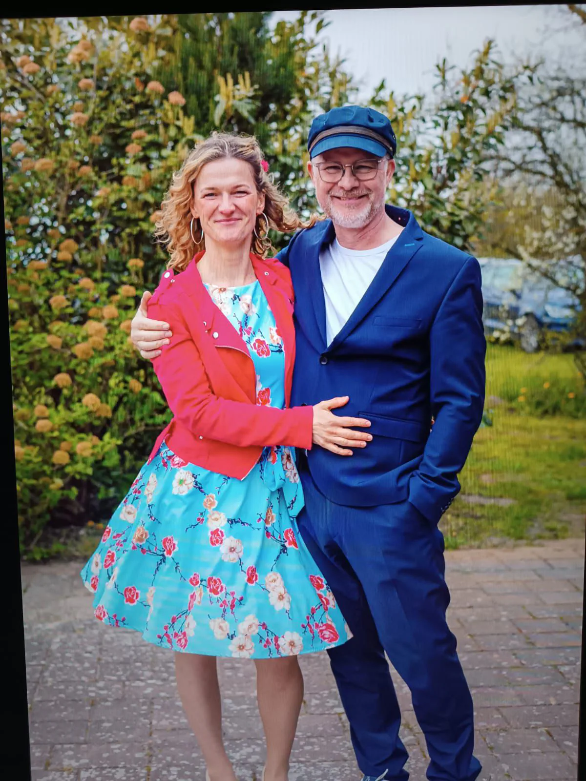 Dana im Blumenkleid und Stefan im blauen Anzug im Garten