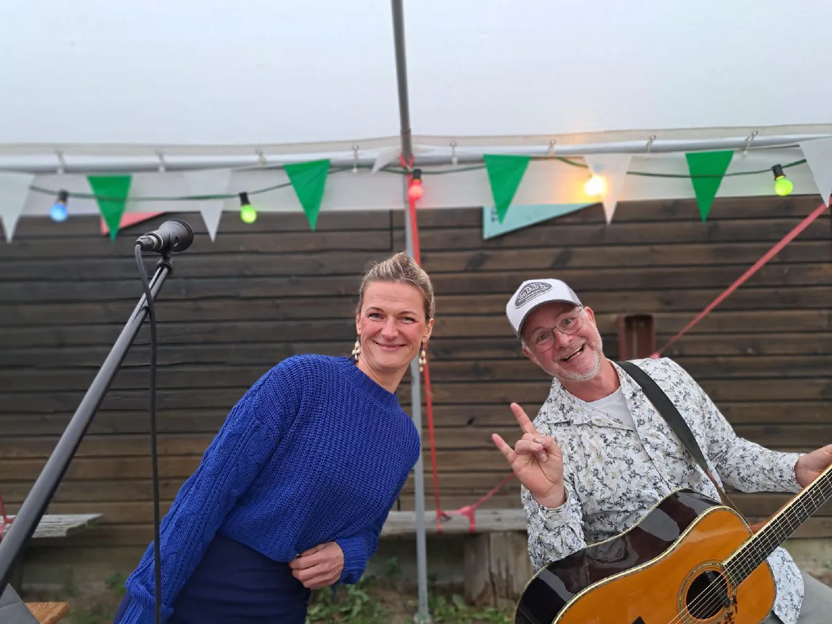 Dana und Stefan lachen unter Wimpeln und Lichterketten in die Kamera