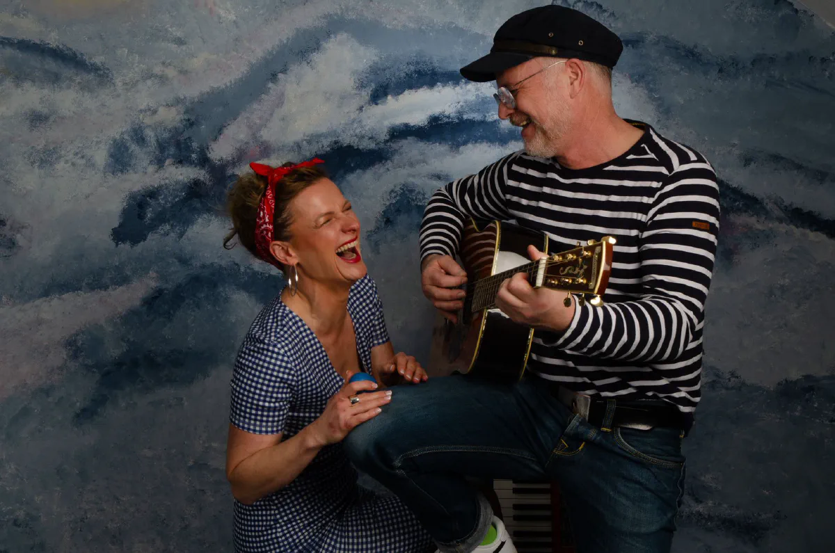 Dana lacht, während Stefan im Matrosenshirt Gitarre spielt