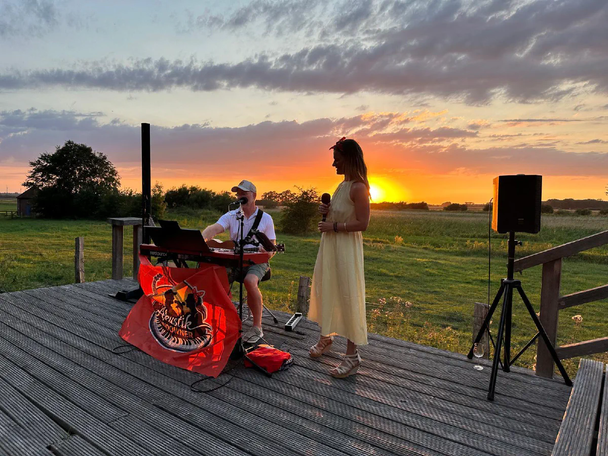 Dana und Stefan spielen auf einer Holzterrasse, während die Sonne über den Feldern untergeht